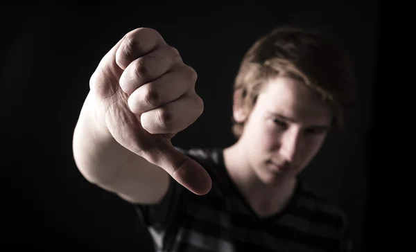 Teen showing thumbs down on the big black background — Stock Photo, Image