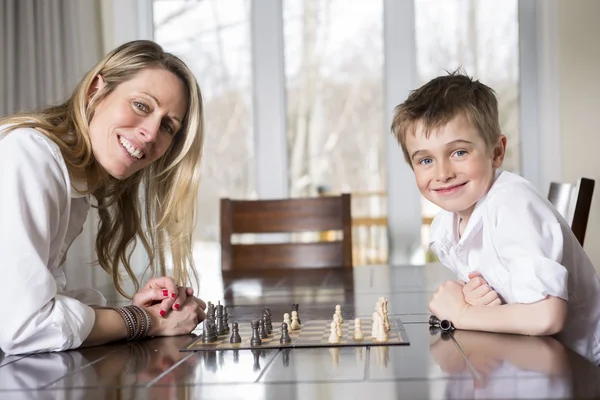 Chico jugando ajedrez en casa con madre — Foto de Stock