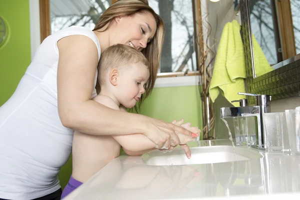 Gelukkig moeder en kind wassen handen met zeep in de badkamer — Stockfoto