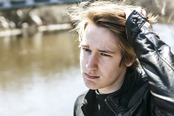 Teen sits outside close to a bridge Leather jacket. — Stock Photo, Image