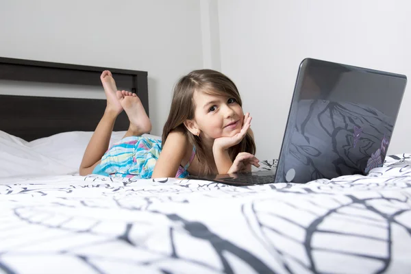 Nine years old child having fun using laptop at her bedroom — Stock Photo, Image