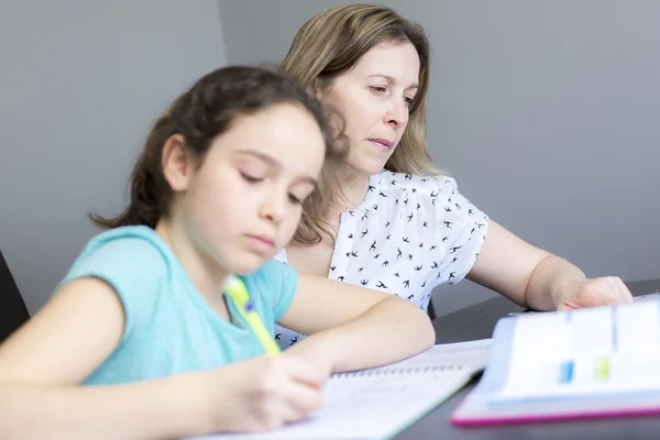 Зріла мати допомагає своїй дитині з домашнім завданням вдома . — стокове фото