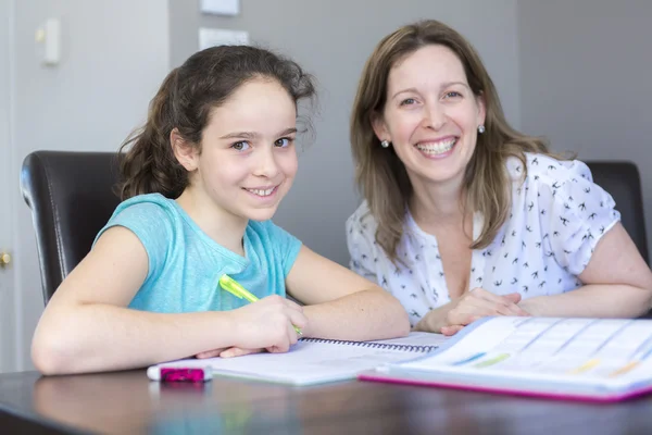 Rijpe moeder haar kind helpen met huiswerk thuis. — Stockfoto