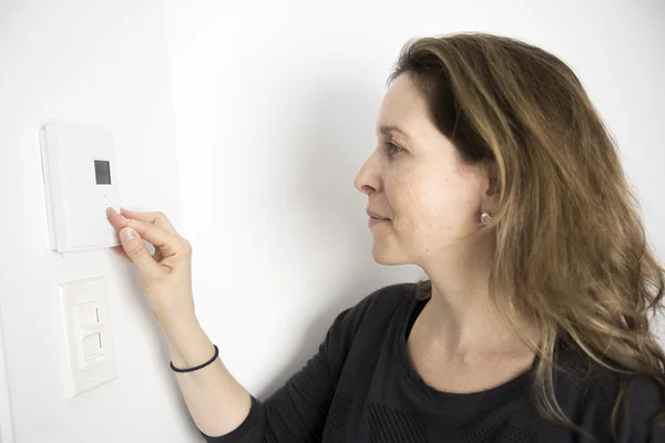 Frau stellt Thermostat an Heizungsanlage ein — Stockfoto