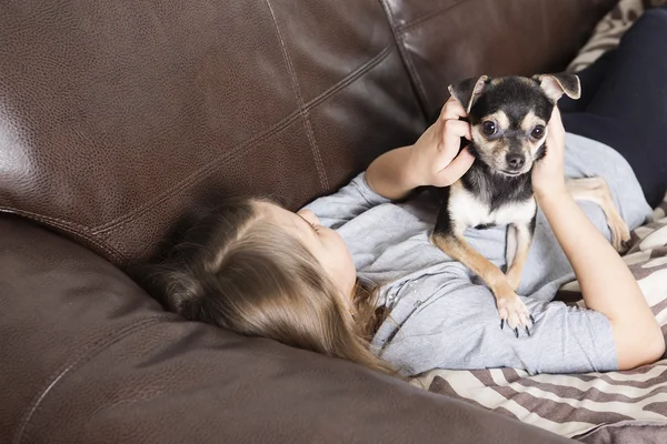 Glückliches Mädchen mit seinem Hund auf dem Sofa — Stockfoto