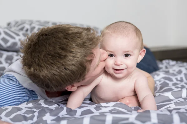 Boldog fiatal apa, a baba az ágyban otthon portréja — Stock Fotó
