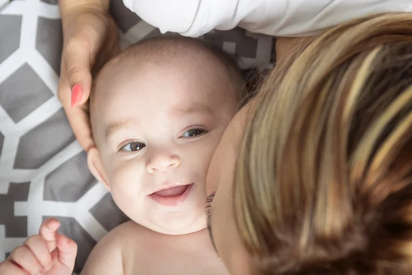 Retrato de madre joven y feliz con un bebé en la cama en casa — Foto de Stock