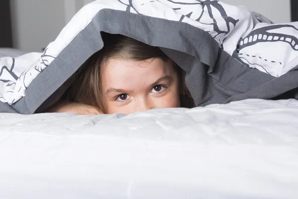 Barn eller tonåring under täcker i sängen — Stockfoto