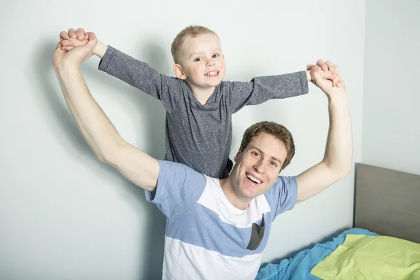 Padre jugar con su hijo niño en la cama en casa — Foto de Stock