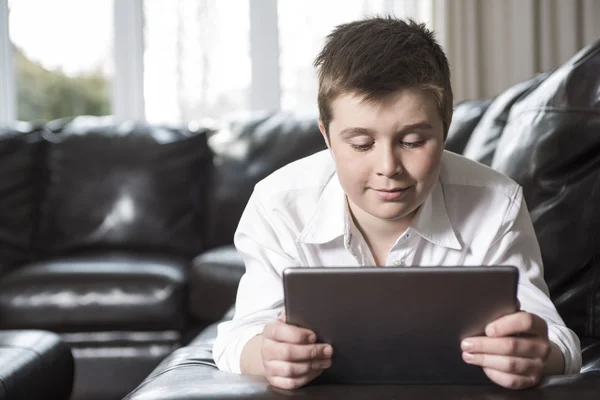 Jeune garçon enfant reposant sur ses mains allongeant un canapé à l'aide d'un ordinateur tablette — Photo