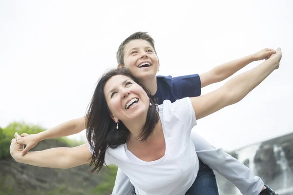 Mother and son playing in front of a waterfall — Stock Photo, Image