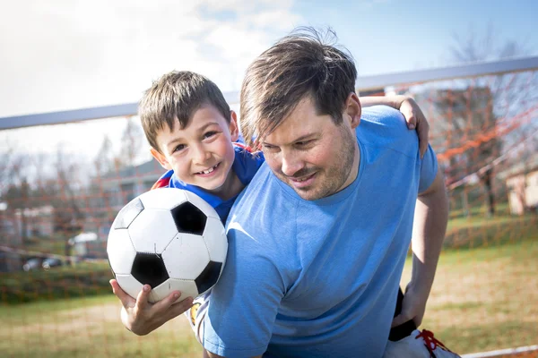 Homem com criança jogando futebol em campo — Fotografia de Stock