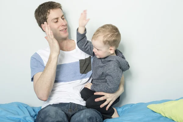 Vader spelen met zijn zoon jongen op het bed thuis — Stockfoto