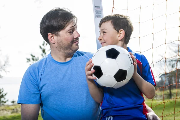 Man med barn spelar fotboll på planen — Stockfoto