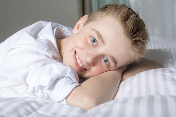 Happy smiling boy lying in bed at home — Stock Photo, Image