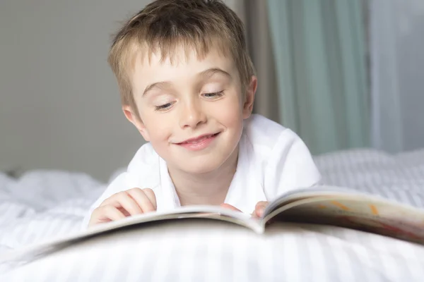 Маленький хлопчик читає перед сном у ліжку — стокове фото
