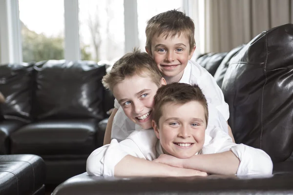 Hermanos abrazándose y jugando en el sofá — Foto de Stock