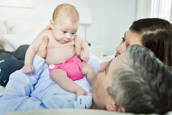 Vanhemmat halaavat vastasyntynyttä vauvaa sängyssä kotona — kuvapankkivalokuva