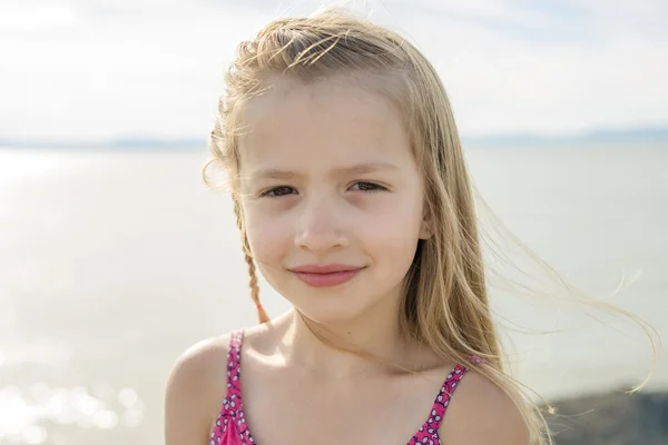 Carino bambina in piedi vicino alla spiaggia al tramonto — Foto Stock