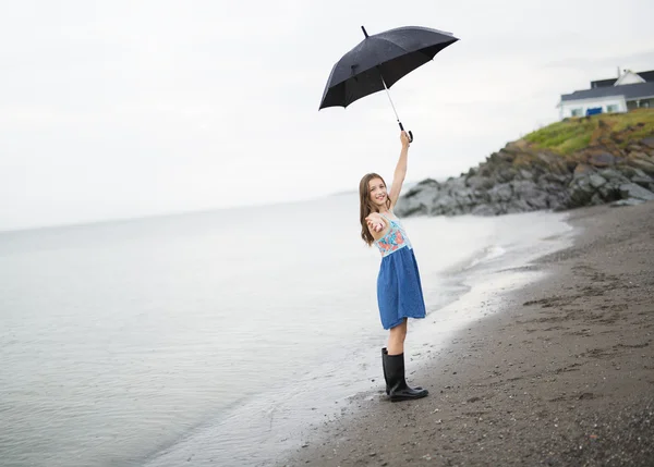 Dívka se těší déšť a baví venku na pláži gray deštivé — Stock fotografie