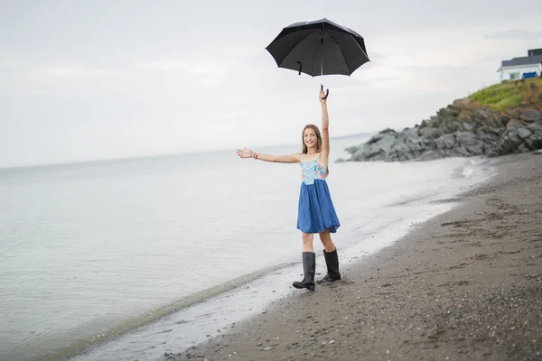 Dívka se těší déšť a baví venku na pláži gray deštivé — Stock fotografie