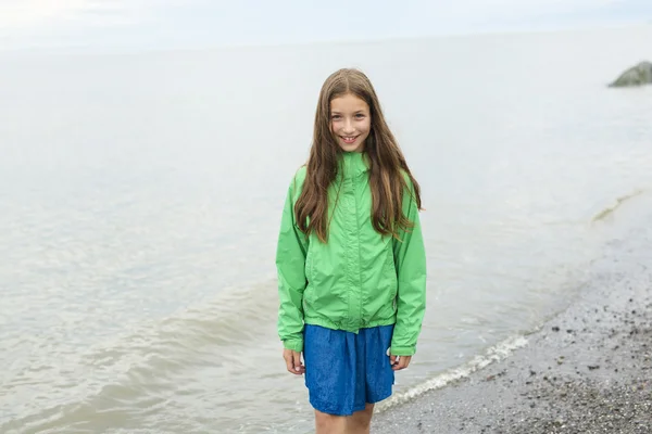Tjej njuter av regnet och att ha kul utanför på stranden en grå regnig — Stockfoto