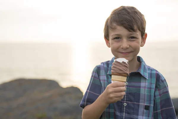 Jongen een heerlijk ijsje eten op de zonsondergang. — Stockfoto
