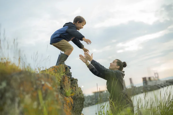 Mamma att hjälpa barn att hoppa av stenar — Stockfoto