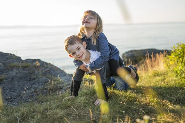 Küçük kardeşim ve kız kardeşi günbatımı yaz aylarında çim oynamak — Stok fotoğraf