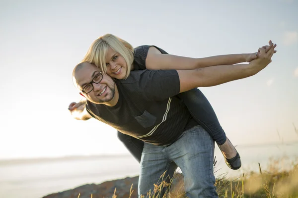 Hermosa pareja en el atardecer habing diversión en la playa — Foto de Stock