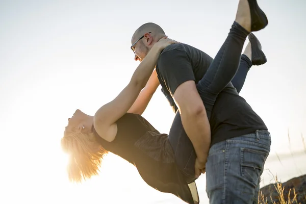 Beautiful couple at the sunset habing fun on seaside — Stock Photo, Image