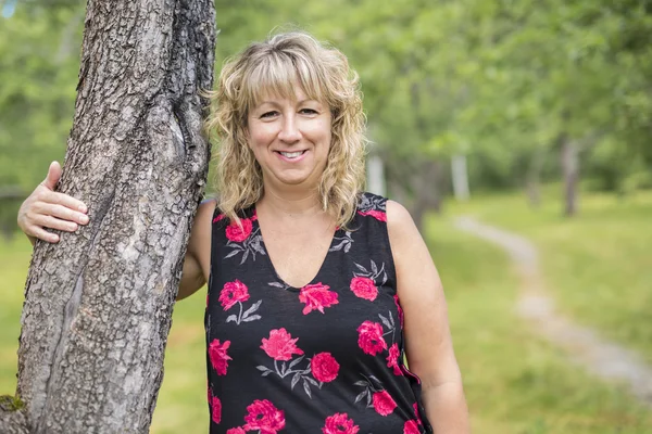 Vrouw die lacht buiten dicht bij een boom in het bos — Stockfoto