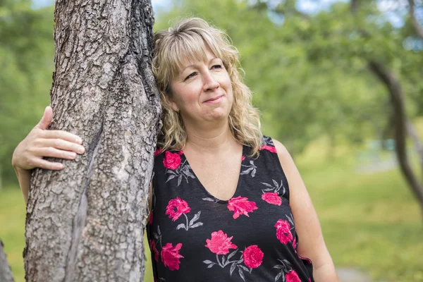 Mujer al aire libre sonriendo cerca de un árbol en el bosque — Foto de Stock