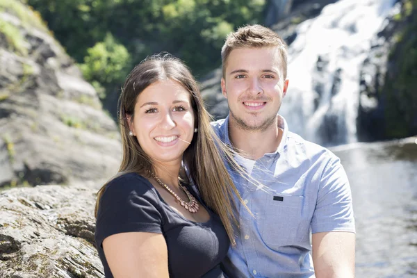 Pareja joven enamorada de la cascada en el fondo — Foto de Stock