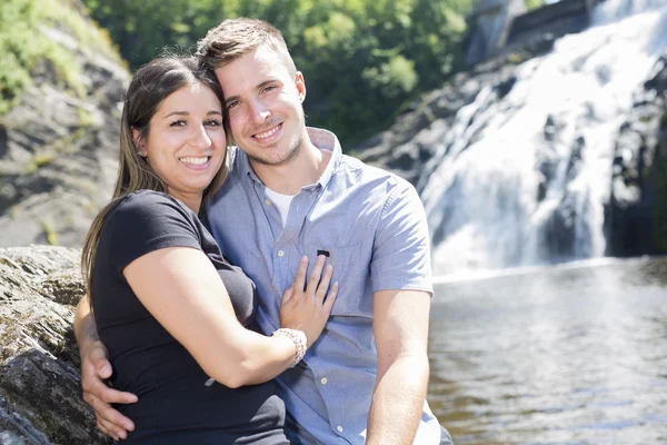 Young couple in love with waterfall on background — Stock Photo, Image