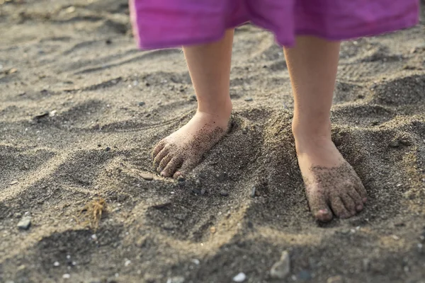 Baby fötter promenader på stranden vid solnedgången — Stockfoto