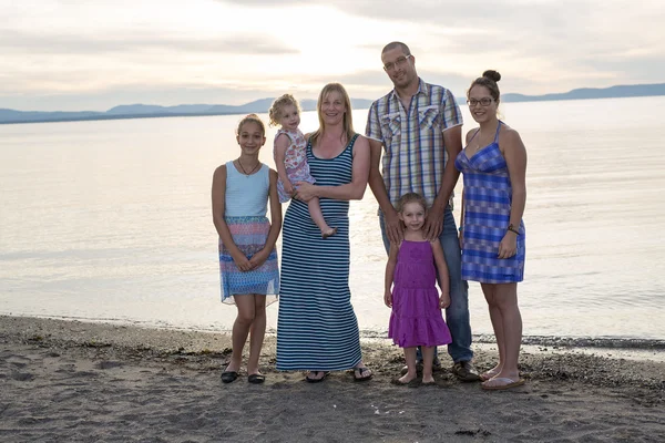 Feliz bela família de pé no pôr do sol da praia — Fotografia de Stock