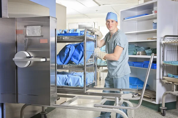 Männer, die an einem Sterilisierungsplatz im Krankenhaus arbeiten und einen Streitwagen aufstellen. — Stockfoto