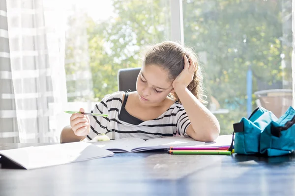 Schoolgirl studying with books on the kitchen table — Stock Photo, Image