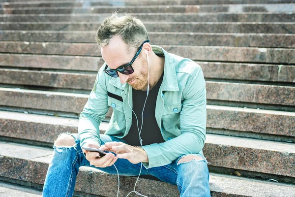 Man listening to the music with earbuds from a smart phone — Stock Photo, Image