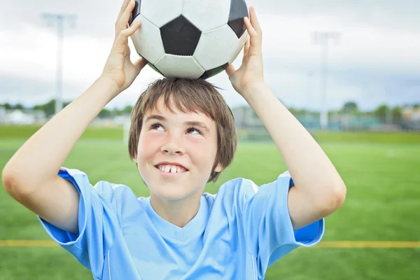 Jonge voetballer met bal op het veld — Stockfoto