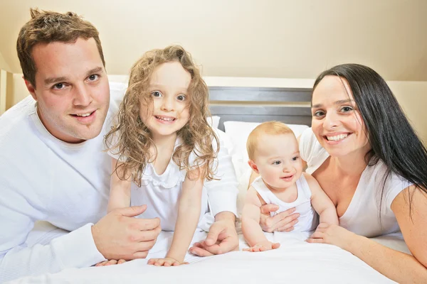 Young family resting together in parents bed — Stock Photo, Image