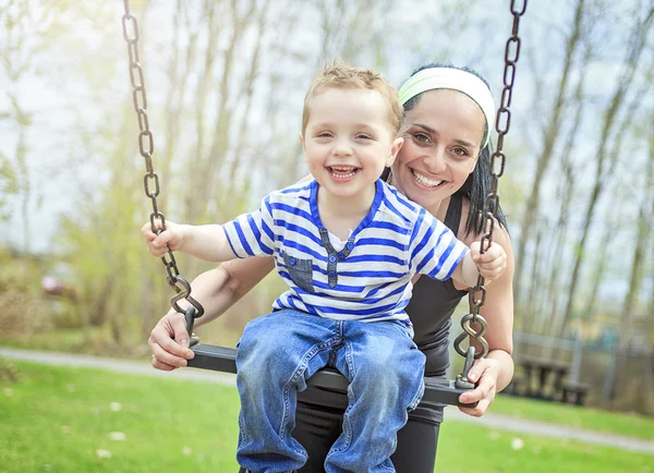 Mother pushing son on swing — Stock Photo, Image