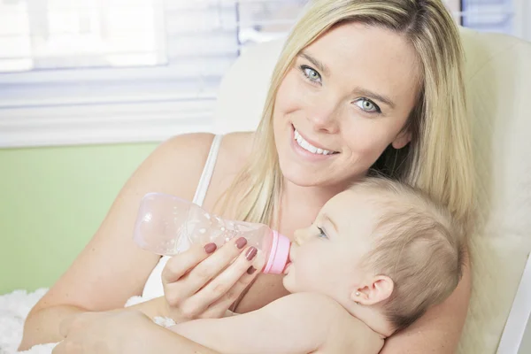 Young mother at home feeding their new baby girl with a milk bot — Stock Photo, Image