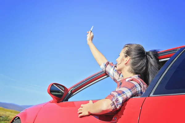Krásná žena, sedící v jejím novém autě, drží klíče. — Stock fotografie
