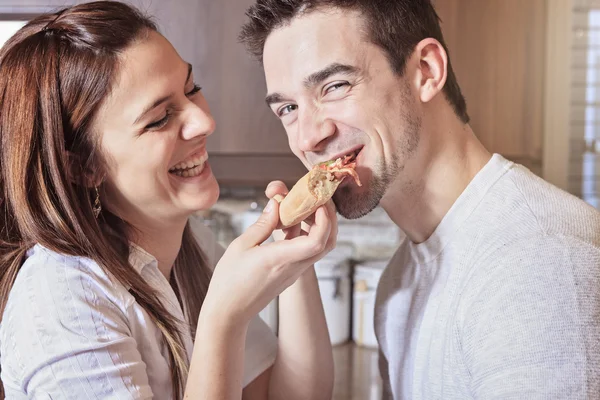 Happy νεαρό ζευγάρι τρώει πίτσα στην κουζίνα — Φωτογραφία Αρχείου