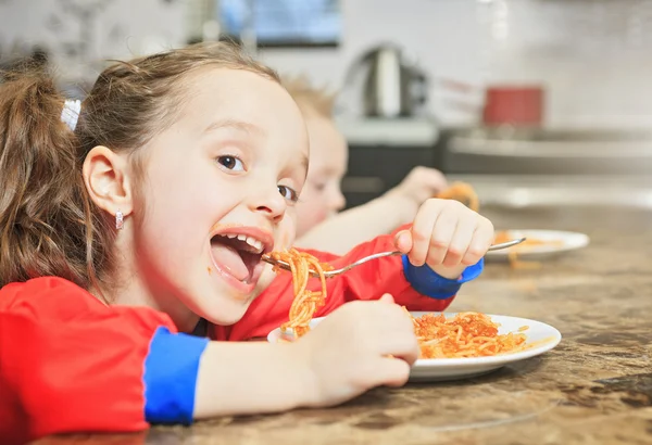 Meisje eten pasta in de keukentafel — Stockfoto