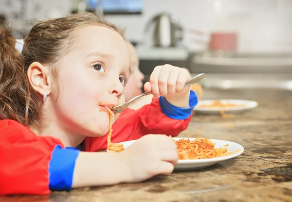Meisje eten pasta in de keukentafel — Stockfoto
