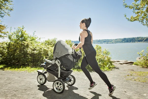 Young mother jogging with a baby buggy — Stock Photo, Image