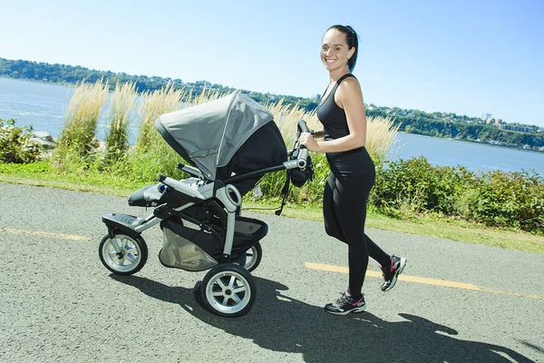 Ung mamma jogging med en baby buggy — Stockfoto